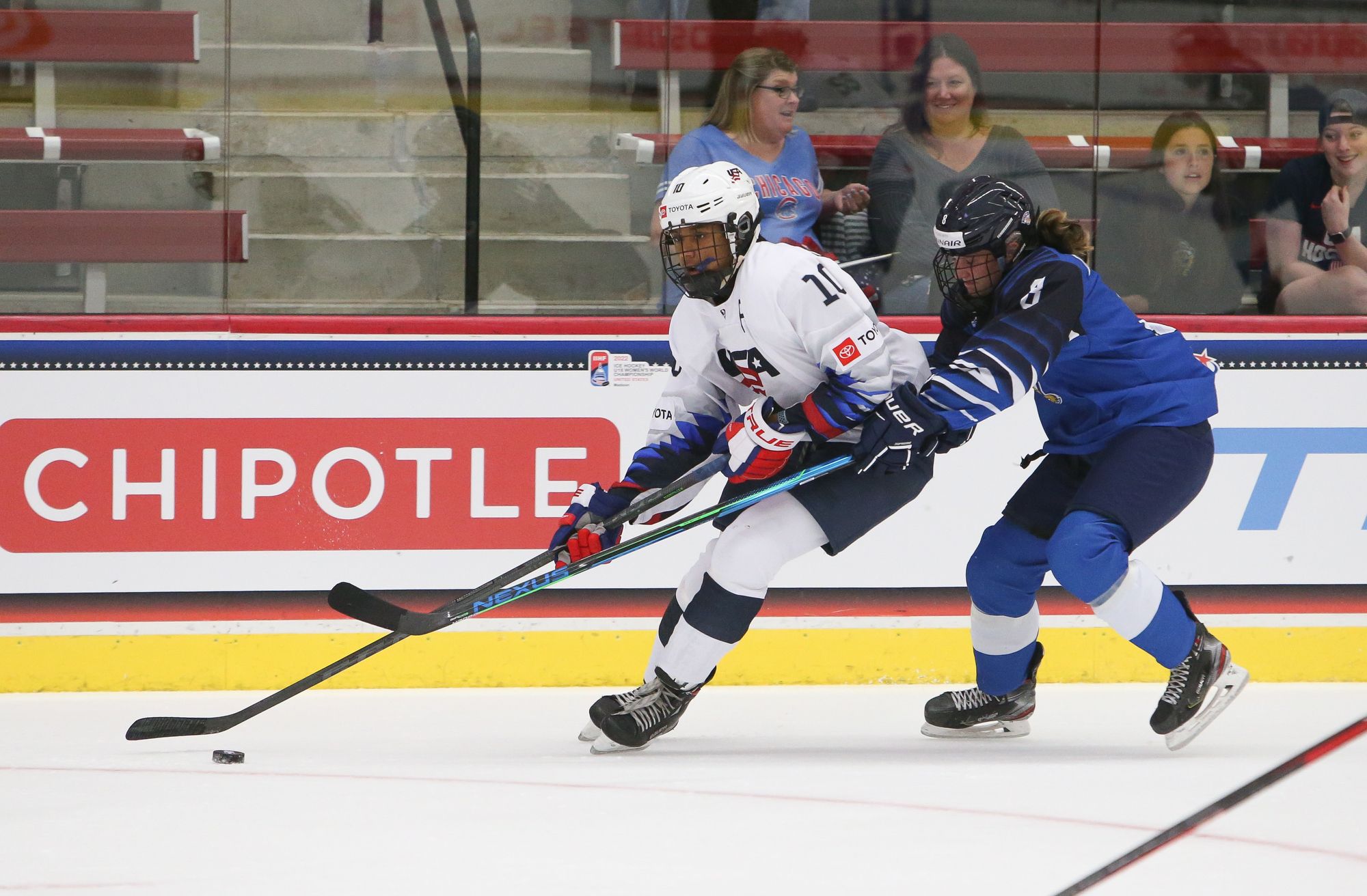 Laila Edwards carries the puck ahead of Tuuli Tallinen. Tallinen is not far behind her, but fails to come close to touching the puck thanks to Edwards' long reach.